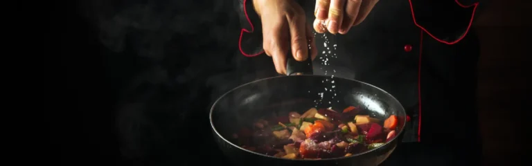 A chef is holding a pan cooking something delicious