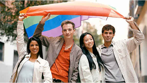 Diverse friends holding rainbow flag supporting lgbtq plus community